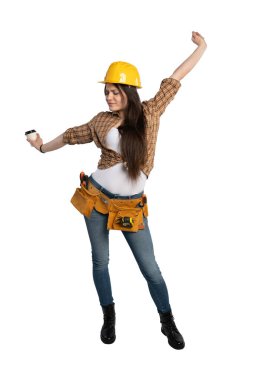 Sarı bir şapka ve alet kemeri takan kadın inşaat işçisi, kahve fincanı tutarken esniyor, yorgun ama çalışmaya hazır görünüyor..