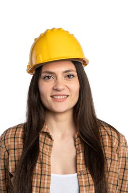 Beyaz arka planda izole edilmiş sarı kasklı ve ekose gömlekli gülümseyen genç kadın inşaat işçisinin yakın plan portresi..
