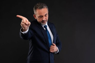 Takım elbiseli ciddi bir işadamı kendinden emin bir şekilde bir tarafa bakıyor, otoritesini dile getiriyor ya da kurumsal bir ortamda yön veriyor..