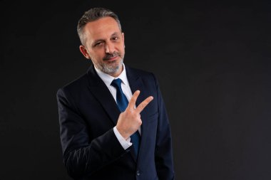Resmi takım elbiseli sırıtan işadamı iki parmağıyla barış ya da zafer jesti yaparak güven, başarı ya da gelişigüzel bir tutum sergiliyor..