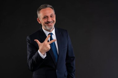 Takım elbiseli, kendine güvenen, gülümseyen ve üç parmağı gösteren, fikirleri, öncelikleri ya da adımları olumlu ve çekici bir tavırla temsil eden olgun bir iş adamı..