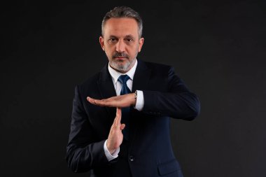 Takım elbiseli ciddi bir işadamı el hareketi yapıyor, iletişimde bir duraksama ya da kopukluk olduğunu gösteriyor..