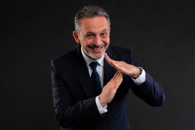 Takım elbiseli kendine güvenen işadamı gülümsüyor ve el hareketi yapıyor, duraklamayı ya da duraklamayı sembolize ediyor.
