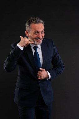 Takım elbiseli neşeli işadamı gülümseyerek ve el kol hareketi yaparak beni ara, iletişimi ya da iletişimi sembolize et..