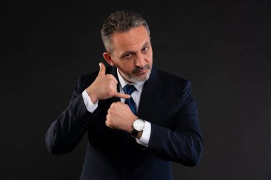 Takım elbiseli kendine güvenen bir işadamı kol saatini işaret ederken 