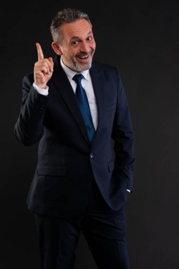 Takım elbiseli neşeli iş adamı işaret parmağı kaldırıyor ve gülümsüyor. Ani bir fikri ya da esin kaynağını simgeliyor..