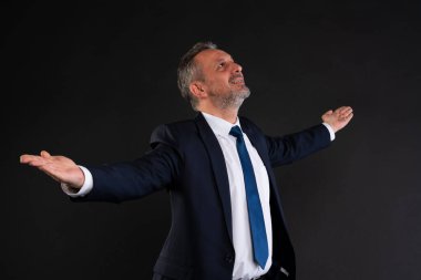 Takım elbiseli, kollarını açıp umutlu ve ilham verici bir ifadeyle yukarıya bakan kendine güvenen bir adam..