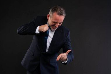 Takım elbiseli bir işadamı, avucunun içine bakarken hayal kırıklığını ya da kızgınlığını ifade ederek kravatını sıkıca bağlıyor. İş stresi ya da baskı kavramı.