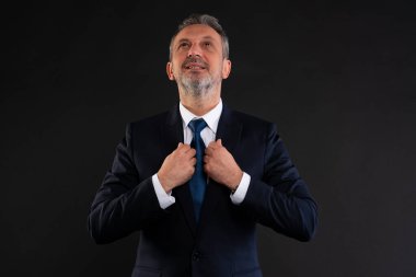 İş adamı umutlu bir ifadeyle yukarı bakarken kravatını düzeltiyor. Motivasyon, yeni başlangıçlar ve kendine güvenin sembolü.