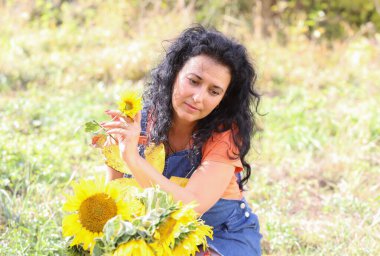 Parlak sonbahar yolunda uzun kıvırcık saçlı, güzel bir esmer. Açık havada çekilmiş.