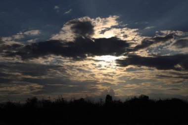 Picture of a dramatic sunset in the fields with dark fluffy clouds clipart