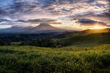 Kosta Rika volkanik manzaralı büyüleyici bir günbatımı. Saf doğal cennet, uçsuz bucaksız yeşil tarlaların volkanların, yağmurların ve inanılmaz günbatımlarının diyarı. Rüya manzarası..