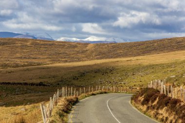 Tipik İrlanda manzarası. Harika doğa manzarası fevkalade. Kayalar, taşlar, dağlar, bulutlu gökyüzü, renkli. Çok popüler bir seyahat yeri. Vadiye giden yol.
