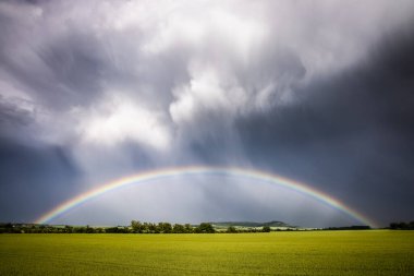 bir alanın üzerinde gökkuşağı, arka planda seyahat yeri