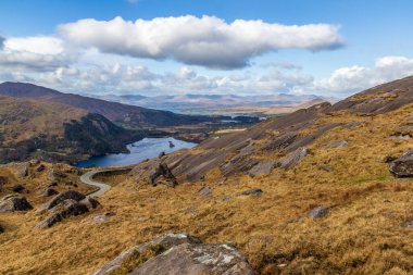 Tipik İrlanda manzarası. Harika doğa manzarası fevkalade. Kayalar, taşlar, dağlar, bulutlu gökyüzü, renkli. Çok popüler bir seyahat yeri. Vadiye giden yol.