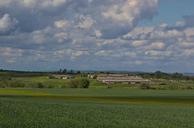 Bahar bozkırlarının uçsuz bucaksız genişliğinde fırtınalı bir gökyüzü. Eski kırsal bir çiftliğin terk edilmiş binaları. Bozkır ovasının uzak ufukları. Tarım konsepti. Odessa bölgesi, Ukrayna.