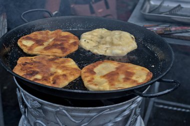 Romanian and Moldovan pies are fried in a large frying pan. Traditional homemade round pies - Placinta. Bakery products. Rustic style. Street Food Fair. Chisinau. Moldova.