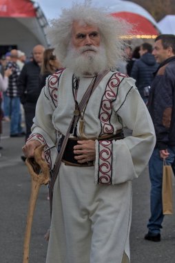 Chisinau, Moldova - October 1, 2022: Portrait of an unknown gray-haired old man with very lush long hair, mustache and beard. An elderly mature man attracts everyone's attention in the city center.
