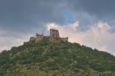 Turniansky Hrad, Slovakya - 26 Haziran 2023: Şatonun kalıntıları göze çarpan koni şeklindeki bir tepenin üzerinde duruyor. Seyahat güzergahı. Kültür Mirası.