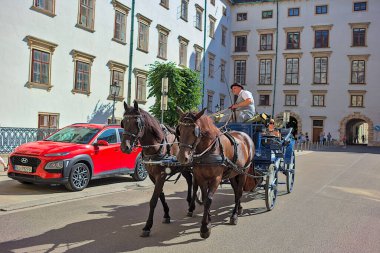 Viyana, Avusturya - 29 Haziran 2023: Viyana 'nın tarihi merkezinde turistlerle dolu at arabası. Çok popüler bir nakliye. Eski şehrin sokakları ve mimarisi.