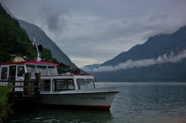 Hallstatt, Avusturya - 1 Temmuz 2023: Sisli bulutlu bir günde Avusturya 'nın Salzkammergut kasabası yakınlarındaki Hallstatt Gölü' nde bir gemi turistleri bekliyor. Popüler hedef.