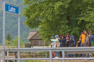 Hallstatt, Avusturya - 1 Temmuz 2023: Rıhtımdaki bir grup turist ünlü Hallstatt kentindeki çarpıcı manzaraya hayran. İnanılmaz mimari ve fantastik manzara ziyaret etmeye değer..