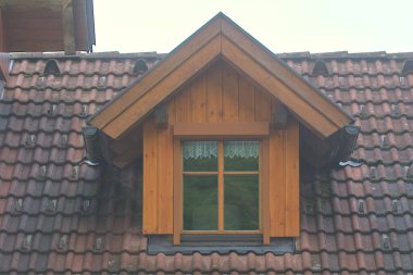 En üst kattaki kiremit çatılı ahşap evin vintage penceresi. Ulusal köy mimarisi. Orijinalliğin tarihsel konsepti. Yeşil turizm. Hallstatt, Avusturya.