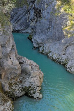 Dar, dolambaçlı bir nehir kayalık bir vadiyi oyuyor. Su, yükselen uçurumların arasından süzülen güneş ışığını yansıtan yanardöner bir turkuaz ışıldar. Fussen, Almanya.