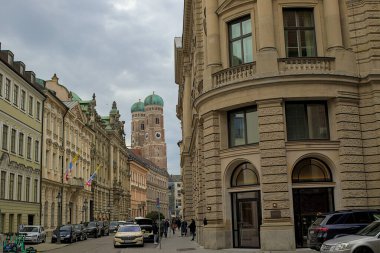 Munich, Germany - October 22, 2024: The iconic spires of the Frauenkirche rise above the historic buildings lining the street. A glimpse into the city's rich history and architectural grandeur. clipart