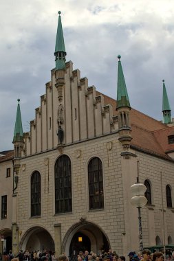 Münih, Almanya - 22 Ekim 2024: Münih 'teki Eski Belediye Binası Gotik kuleleri vuruyor. Ön cephesi karmaşık pencere ve heykellerle dolu. Aşağıdaki kalabalık meydanın canlılığını artırıyor..