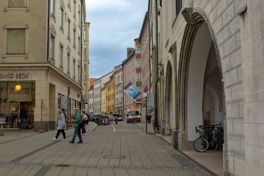 Munich, Germany - October 22, 2024: A street in Munich lined with colorful old buildings. The building on the right is part of the Old Town Hall. Locals and tourists stroll through this vibrant area. clipart