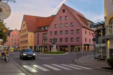 Fussen, Almanya - 21 Ekim 2024: Fussen kavşağında Kral II. Ludwig 'in heykeli bulunuyor. Yanındaki Sonne Oteli sıcak sarı yüzüyle duruyor. Kavşakta bir araba hareket ediyor..