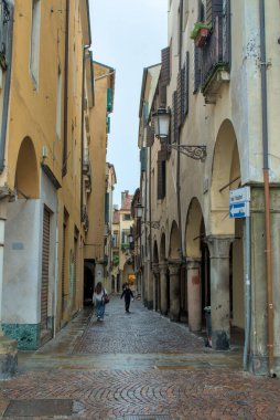 Padova, İtalya - 17 Ekim 2024: Çakıl taşları son yağmurdan parlıyor. Eski cepheler arasında dar sokaklar uzanıyor. Birkaç gezgin kemerlerin altında sürükleniyor..