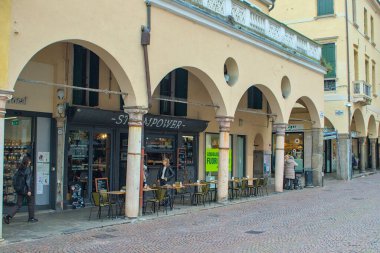 Padova, İtalya - 17 Ekim 2024: Steampower - Caffetteria, Specialty Coffee Padova. İnsanlar klasik kemerlerin altında kahveyi severler. Çekici kaldırımlı caddede alışveriş kuyruğu. Bir İtalyan kasabasında samimi bir an..