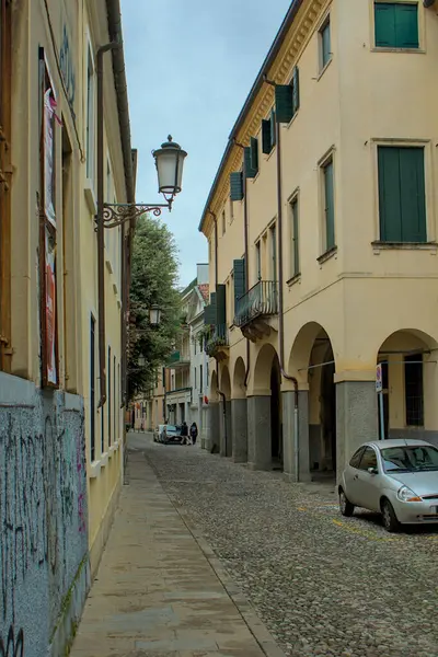 Padua, İtalya - 17 Ekim 2024: Padua, İtalya 'da büyüleyici dar bir cadde, kemerli geçitleri ve antik binaları olan tarihi mimariyi sergiliyor. Yeşil kepenkler geçmişin hikayelerini koruyor..