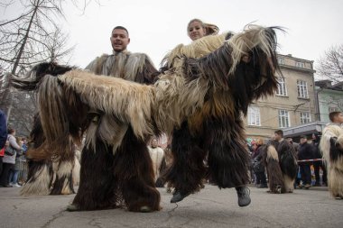 Bulgaristan 'ın Kyustendil kenti - 10 Şubat 2024: Bulgaristan' ın Kyustendil kentinde düzenlenen maskeli balo festivalinin birincisi. Bulgar folklor kostümü giymiş bir adam ve bir kadın bakır çanlar eşliğinde dans ediyor ve doğurganlık ve sağlık ayini yapıyorlar..