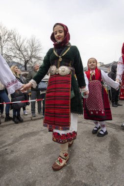 Bulgaristan 'ın Kyustendil kenti - 10 Şubat 2024: Bulgaristan' ın Kyustendil kentinde düzenlenen maskeli balo festivalinin birincisi. Bulgar halk dansları giyinmiş kadınlar doğurganlık ve sağlık ayini düzenliyor..