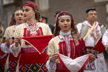 Bulgaristan 'ın Kyustendil kenti - 10 Şubat 2024: Bulgaristan' ın Kyustendil kentinde düzenlenen maskeli balo festivalinin birincisi. Bulgar halk dansları giyinmiş kadınlar doğurganlık ve sağlık ayini düzenliyor..