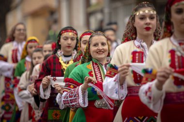Bulgaristan 'ın Kyustendil kenti - 10 Şubat 2024: Bulgaristan' ın Kyustendil kentinde düzenlenen maskeli balo festivalinin birincisi. Bulgar halk dansları giyinmiş kadınlar doğurganlık ve sağlık ayini düzenliyor..