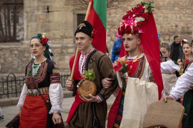 Bulgaristan 'ın Kyustendil kenti - 10 Şubat 2024: Bulgaristan' ın Kyustendil kentinde düzenlenen maskeli balo festivalinin birincisi. Damat ve gelin gibi Bulgar ulusal kostümleri giyen erkekler, bir doğurganlık ve sağlık ayini düzenleyip dans ediyorlar..
