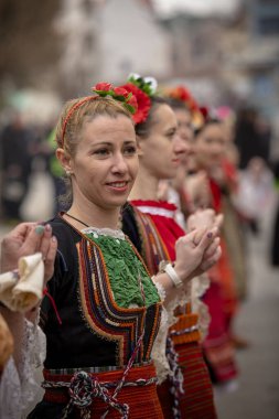 Bulgaristan 'ın Kyustendil kenti - 10 Şubat 2024: Bulgaristan' ın Kyustendil kentinde düzenlenen maskeli balo festivalinin birincisi. Bulgar halk dansları giyinmiş kadınlar doğurganlık ve sağlık ayini düzenliyor..