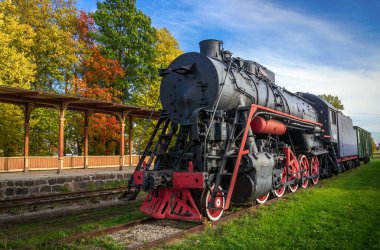 Haapsalu şehrindeki demiryolu müzesi. Ön planda eski lokomotif ve tren istasyonu var. Sahne, sonbahar sezonunda çekildi. Estonya.