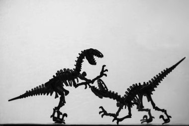 Hafif bir arkaplana karşı siluetlenmiş tahta Velociraptors modellerinin tek renkli görüntüsü