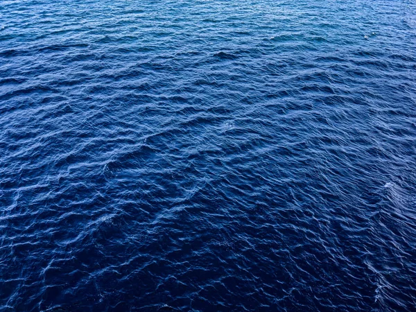 Blue water background. Wavy sea water surface. Close-up of blue water surface in the deep ocean. Blue background.