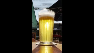 Bardakta köpüklü taze bira. Bir bardak dolusu altın bira ve hafif bir yaz arkaplanı..