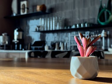 Pembe sulu bitkisi olan küçük beyaz vazo. Bulanık çubuğun arkaplanı.