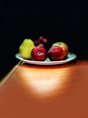 Masanın üzerinde siyah arkaplan olan meyve tabağı..