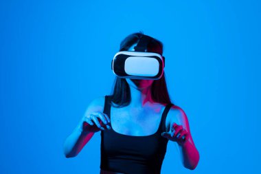 Modern çalışma stüdyosunda siyah bluzlu esmer kadın sanal gerçeklik gözlüğü takıyor.