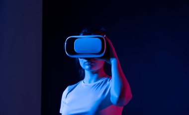 Elleri havada genç esmer bir kadın sanal gerçeklik gözlüğü kullanıyor. Modern gelecek teknolojisi