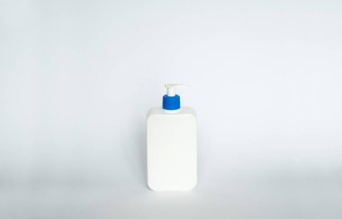 Beyaz sıvı konteynır, jel, losyon, krem, şampuan için plastik plastik şişe, beyaz arka planda mavi pompalı banyo köpüğü. Kopya alanı ile kozmetik paketleme